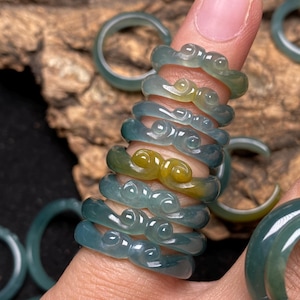 May include: A stack of jade rings with a swirling design. The rings are green and yellow and have a glossy finish.