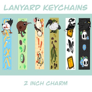 May include: Six colorful lanyard keychains featuring different animal illustrations. Each keychain has a 2 inch charm with a unique design. The charms include a kiwi, a cockatoo, a bird with a black beak, a bird with a yellow beak, a black bird with a skull, and a seagull.