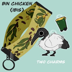 May include: A green and gold patterned fabric strap with the text "BIN CHICKEN (IBIS)" and two charms: a white bird with a black head and a green trash can.