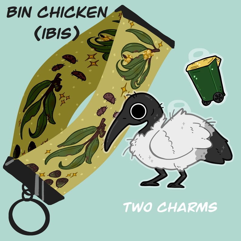 May include: A green and gold patterned fabric strap with the text "BIN CHICKEN (IBIS)" and two charms: a white bird with a black head and a green trash can.