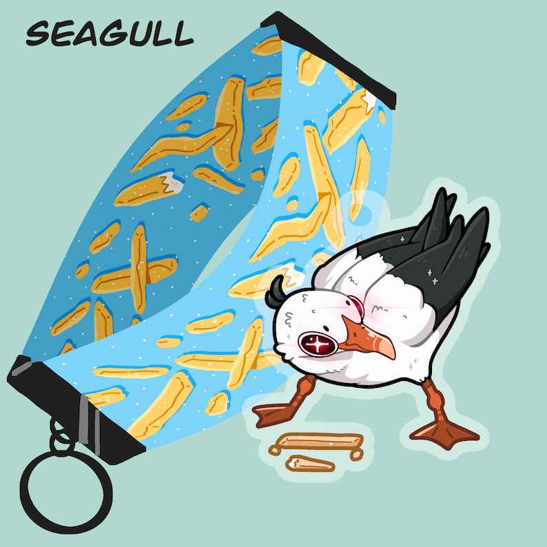 May include: A blue and yellow patterned phone strap with a cartoon seagull design. The seagull is white with black wings and a red eye. The strap has a metal ring for attaching to a phone.