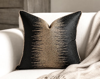 May include: A square throw pillow featuring a black and gold beaded design. The center of the pillow has a vertical band of gold beads that transitions into black beads toward the edges, creating a textured, gradient pattern with gold piping.