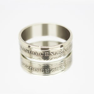 May include: A silver ring made from a coin with the inscription "BANCO CENTRAL" on the band.