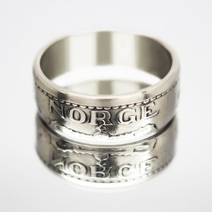 May include: A silver ring made from a Norwegian coin. The ring features the word "NORGE" engraved around the band.