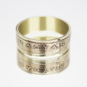 May include: A gold ring made from two stacked Hungarian coins. The top coin features the inscription "MAGYAR" and the bottom coin features the inscription "MAGYAR" in reverse.