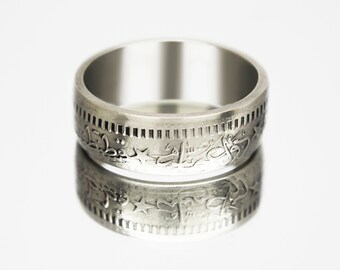 May include: A silver ring made from a coin with Arabic script and stars around the edge.
