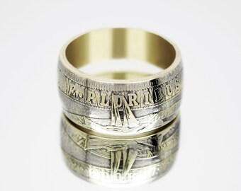 May include: A silver ring with a gold band, featuring the inscription "E PLURIBUS UNUM" around the edge. The ring is made from a repurposed US silver dollar coin.