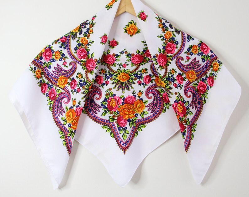 May include: White cotton scarf with a paisley pattern in shades of pink, orange, yellow, and blue.