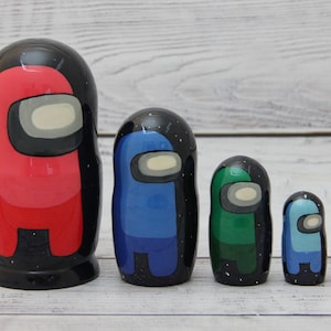 May include: A set of five nesting dolls, each painted to resemble a different coloured character from the popular video game Among Us. The dolls are arranged in order of size, with the largest doll on the left and the smallest doll on the right. The dolls are painted in red, blue, green, light blue, and orange.