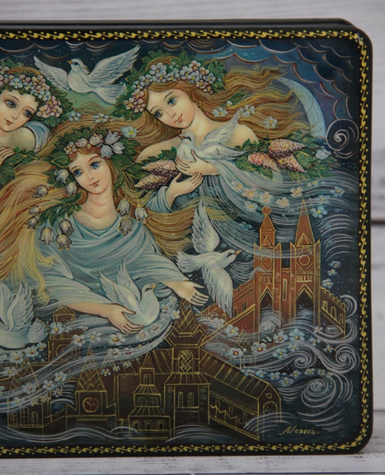 May include: A hand-painted wooden box with a scene of three women with flowing hair and white doves, set against a backdrop of a city with a church steeple. The box is decorated with a gold border and the artist's signature.
