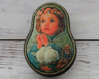 May include: A wooden nesting doll with a painted image of a young girl with a flower crown, holding two white doves. The doll is painted in a traditional Russian style with intricate details.