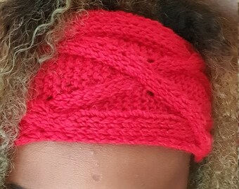 Könnte beinhalten: Ein rotes gestricktes Stirnband mit einem geflochtenen Muster. Das Stirnband wird von einer Person mit grün und blau gefärbtem Haar getragen.