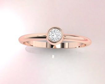 May include: A simple rose gold band ring with a single round bezel-set diamond.