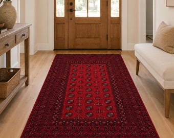 May include: A red and black patterned runner rug with a central medallion design and fringed edges. The rug is placed in a hallway with a wooden console table, a mirror, and a bench.