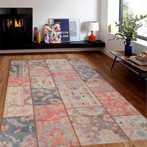 May include: A rectangular patchwork rug with a variety of floral and geometric patterns in shades of pink, blue, beige, and gray. The rug is made up of multiple rectangular sections, creating a unique, textured look. The rug is placed on a wooden floor.