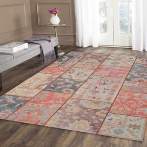 May include: A rectangular area rug with a patchwork design. The rug features a variety of colors, including red, blue, and orange, arranged in a geometric pattern. The rug is placed on a hardwood floor.