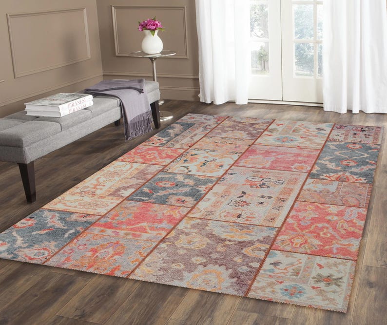May include: A rectangular area rug with a patchwork design. The rug features a variety of colors, including red, blue, and orange, arranged in a geometric pattern. The rug is placed on a hardwood floor.