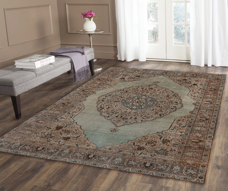 Pu&ograve; includere: Un tappeto in stile vintage con un centro blu chiaro e intricati motivi marroni e beige. Il tappeto ha un aspetto sbiadito e usurato, che gli conferisce un aspetto unico e antico.