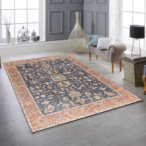 K&ouml;nnte beinhalten: Ein dunkelblauer Teppich mit einem detaillierten Blumenmuster in Beige-, Creme- und Gr&uuml;nt&ouml;nen. Der Teppich hat einen breiten Rand mit einem sich wiederholenden Muster in Orange- und Cremet&ouml;nen.