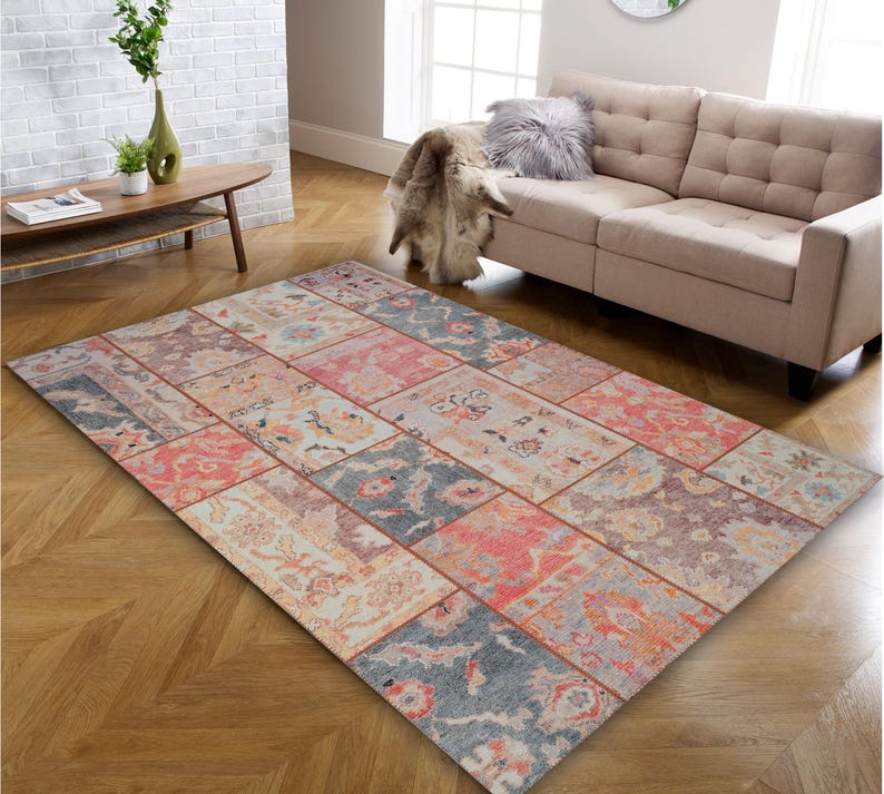 May include: A rectangular patchwork rug with a distressed, vintage look. The rug features a variety of rectangular patterns in shades of pink, blue, and beige. The rug is placed on a hardwood floor.