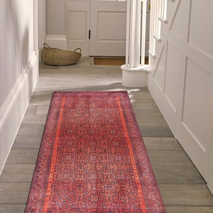 May include: A red and blue patterned runner rug with a geometric design. The rug is placed in a hallway with white walls and wooden floors.