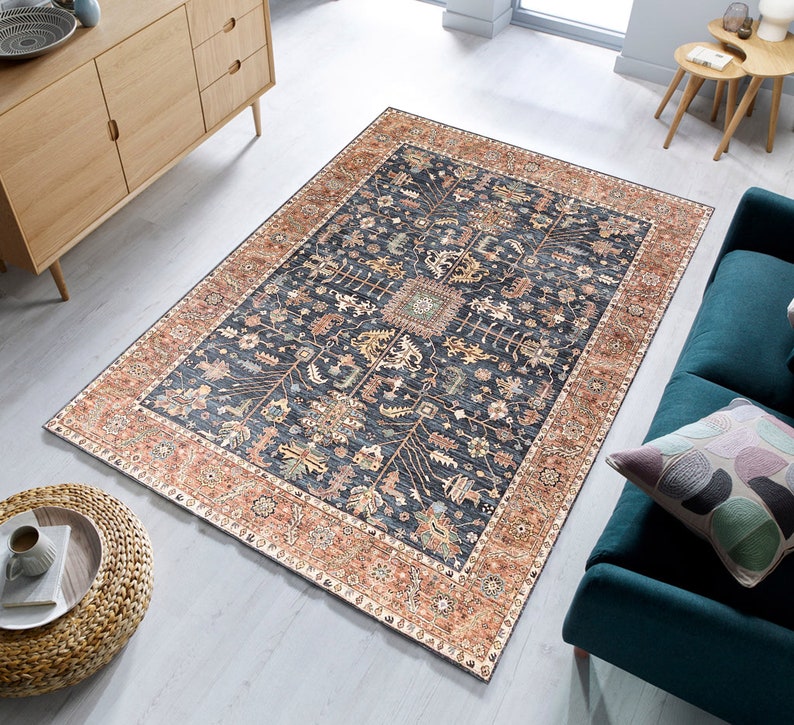 K&ouml;nnte beinhalten: Ein dunkelblauer Teppich mit traditionellem persischem Design. Der Teppich hat einen cremefarbenen und rostbraunen Rand mit komplizierten Blumenmustern. Der Teppich liegt auf einem hellen Holzboden.