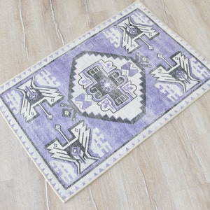 May include: A purple and white patterned rug with a geometric design. The rug has a cream border.