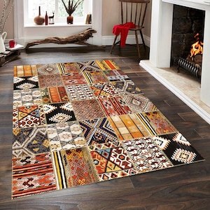 May include: A colorful patchwork rug with geometric patterns in shades of orange, brown, black, and white. The rug has a distressed, vintage look and is perfect for adding a bohemian touch to any room.