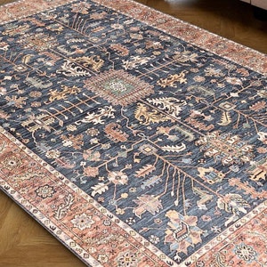 K&ouml;nnte beinhalten: Ein blauer und roter Teppich mit traditionellem Muster. Der Teppich hat einen dunkelblauen Hintergrund mit komplizierten floralen und geometrischen Mustern in Rot-, Orange- und Cremet&ouml;nen.