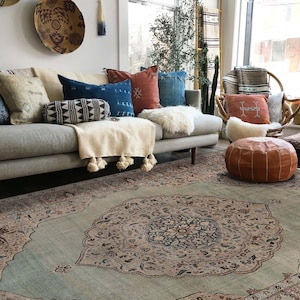 Pu&ograve; includere: Un tappeto blu chiaro con un grande motivo floreale intricato in tonalit&agrave; di marrone, beige e blu. Il tappeto si trova in un soggiorno con un divano grigio e una variet&agrave; di cuscini.