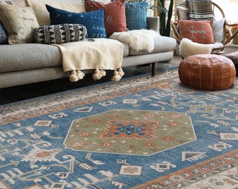 Könnte beinhalten: Ein blauer und grüner Teppich mit geometrischem Muster. Der Teppich hat einen cremefarbenen Rand mit orangefarbenen und braunen Akzenten. Der Teppich befindet sich in einem Wohnzimmer mit einer Couch und Kissen.