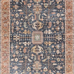 K&ouml;nnte beinhalten: Ein blauer und orangefarbener Teppich mit traditionellem Muster. Der Teppich hat ein zentrales Medaillon und durchgehende, komplizierte Details.