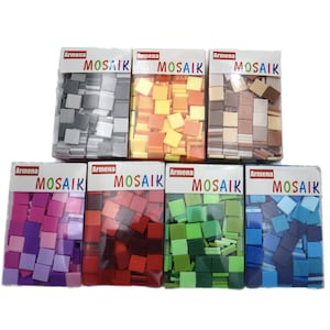 Puede incluir: Ocho cajas de pequeñas baldosas de mosaico de vidrio de colores. Cada caja está etiquetada con "Armenia Mosaik" y contiene un color diferente de baldosas, incluyendo gris, naranja, marrón, rosa, rojo, verde, azul y azul claro.