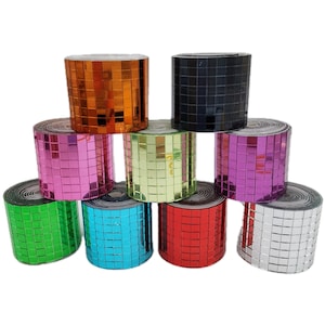 Könnte beinhalten: Eine Sammlung farbenfroher Mosaikfliesenrollen. Die Rollen sind in verschiedenen Farben erhältlich, darunter Orange, Schwarz, Rosa, Grün, Blau, Rot und Silber. Jede Rolle besteht aus kleinen, quadratischen Fliesen.