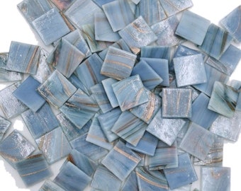 May include: A collection of small, square mosaic tiles in shades of blue with gold and white veining. The tiles are scattered, showcasing their marbled appearance. These decorative tiles are suitable for various craft and home decor projects.