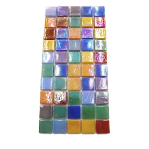 Op de afbeelding: Een vel met iriserende glazen mozaïektegels in verschillende kleuren, waaronder blauw, groen, geel, orange en rood. De tegels zijn in een rasterpatroon gerangschikt.
