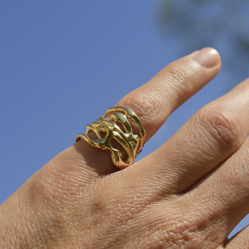 Bold organic gold ring with fluid, sculptural openwork design, handcrafted for a modern artistic style.