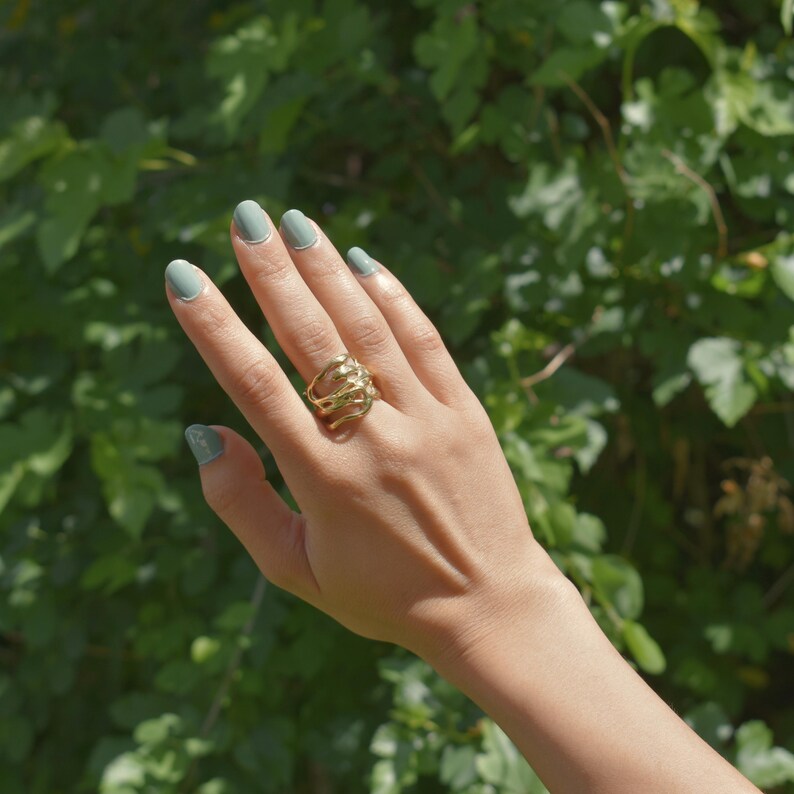 Bold organic gold ring with fluid, sculptural openwork design, handcrafted for a modern artistic style.