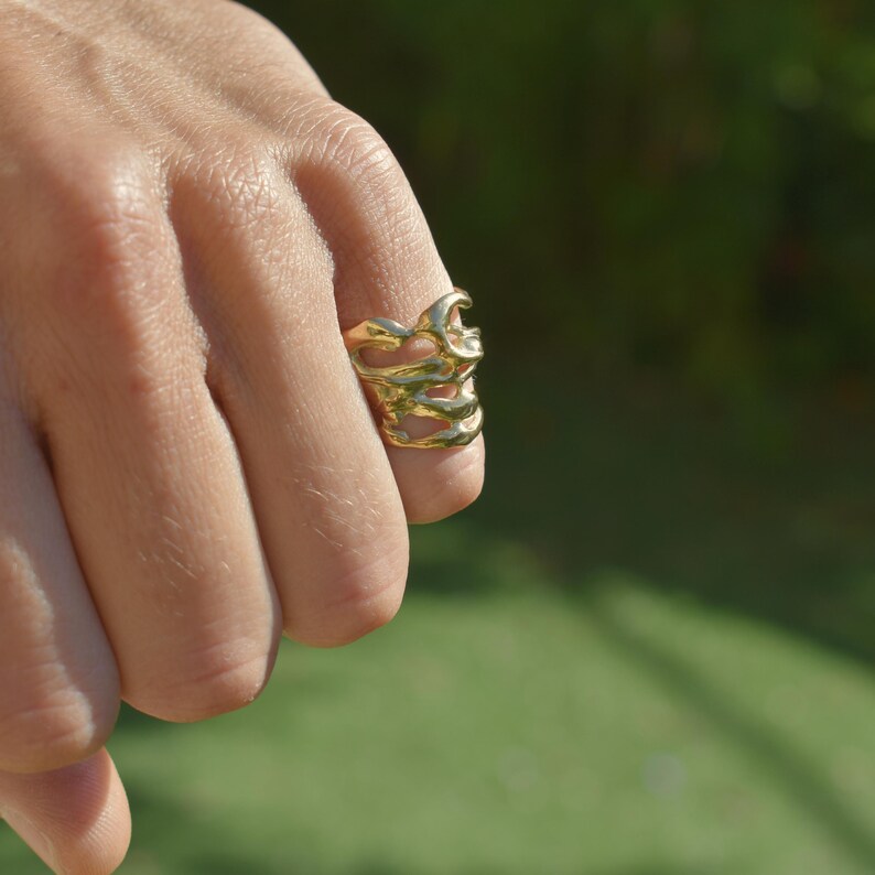 Bold organic gold ring with fluid, sculptural openwork design, handcrafted for a modern artistic style.