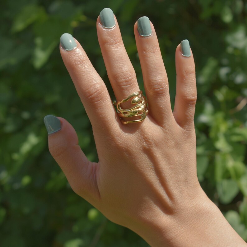 Bold organic gold ring with fluid, sculptural openwork design, handcrafted for a modern artistic style.