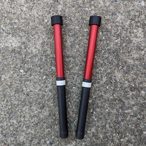 May include: Two red drumsticks with black tips and white bands.