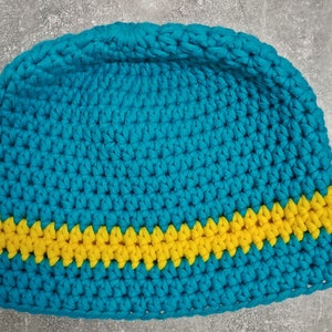 Puede incluir: Un gorro de punto azul con una franja amarilla alrededor del borde.