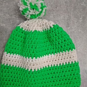 Puede incluir: Gorro de punto de color verde y blanco con un pompón blanco en la parte superior.
