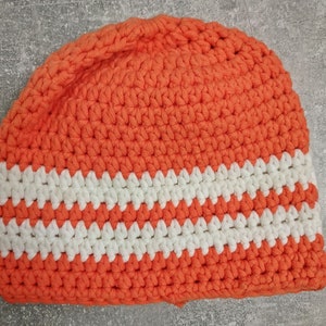 Puede incluir: Gorro de punto de ganchillo naranja y blanco con un patrón de rayas.