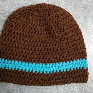 Puede incluir: Gorro de punto marrón con una franja azul.