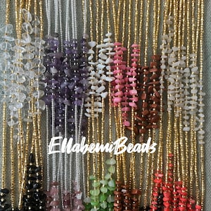 May include: A variety of beaded necklaces with different colored stones. The necklaces are made with gold and silver chains and feature various colors, including clear, purple, white, pink, brown, black, green, and red.