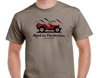 May include: A brown t-shirt with a red jeep illustration and the text "Aged to Perfection."  The jeep is driving up a mountain road.