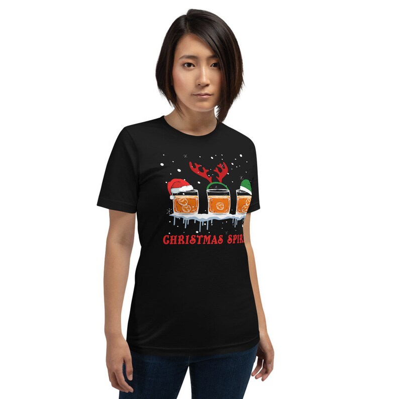 May include: Black t-shirt with a graphic of three glasses of orange liquid with Christmas hats and reindeer antlers. The text "Christmas Spirit" is printed below the glasses.