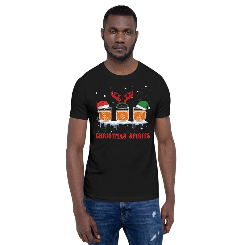May include: Black t-shirt with a Christmas-themed design featuring three glasses of alcohol with Santa hats and reindeer antlers. The text "CHRISTMAS SPIRITS" is printed below the glasses.