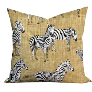 May include: A tan throw pillow with a black and white zebra print. The pillow is made of a textured fabric and has a zipper closure.